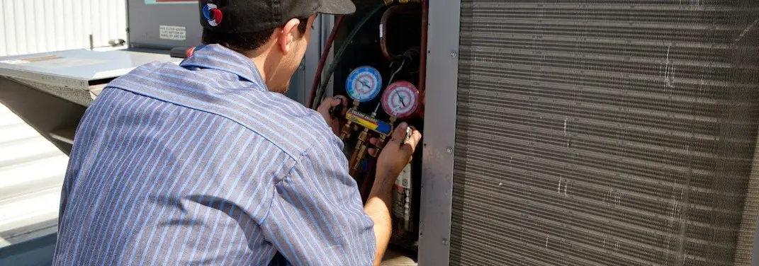 HVAC technician servicing a condenser unit in Timberwood Park
